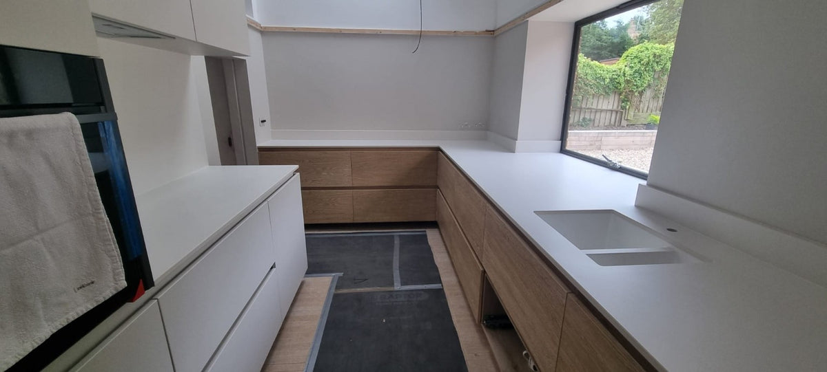 Completed handleless kitchen cabinetry around a large window